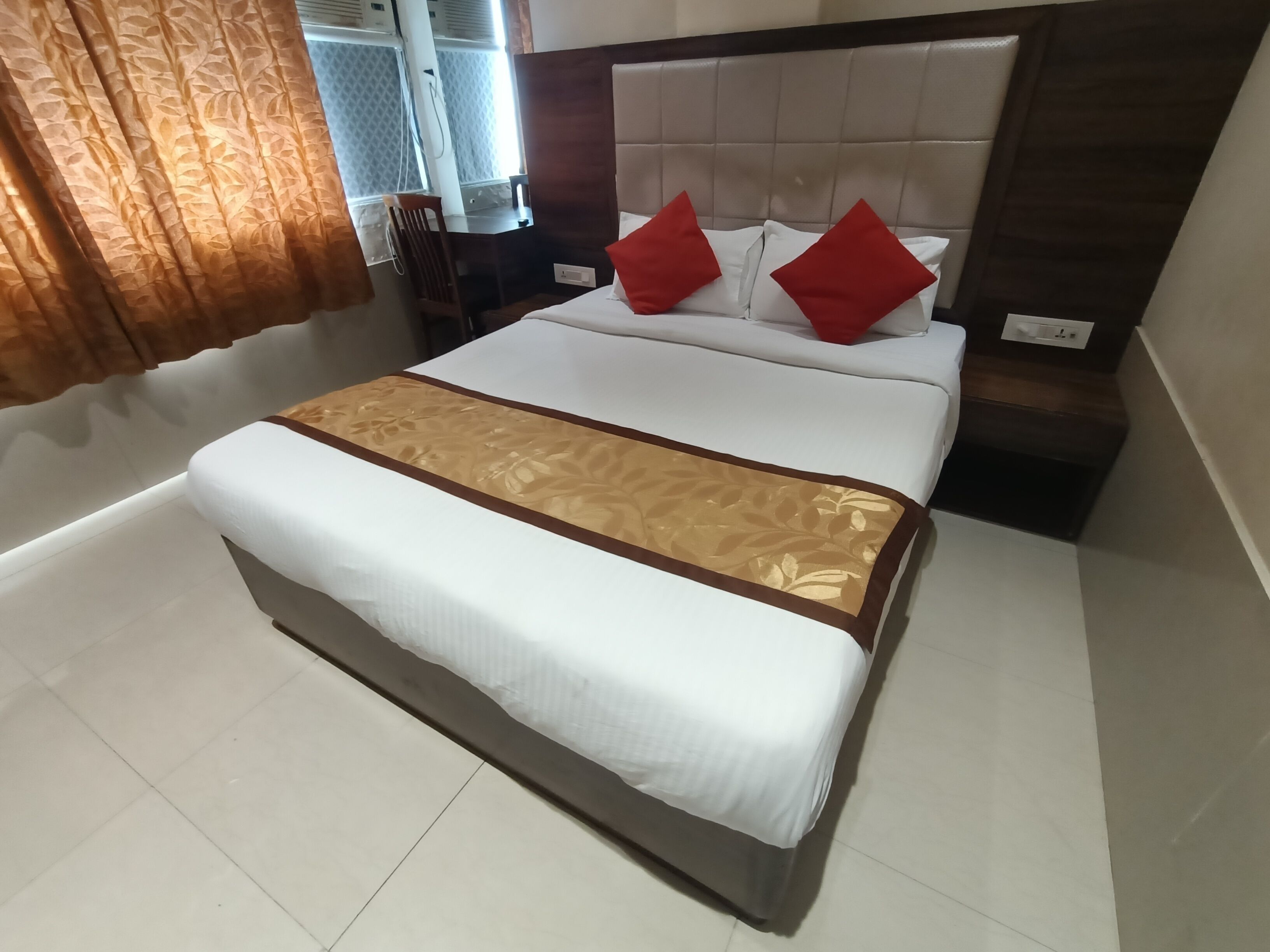 Ein Hotelzimmer mit einem großen Bett, einem Holzkopfbrett und einem kleinen Schreibtisch mit Stuhl.