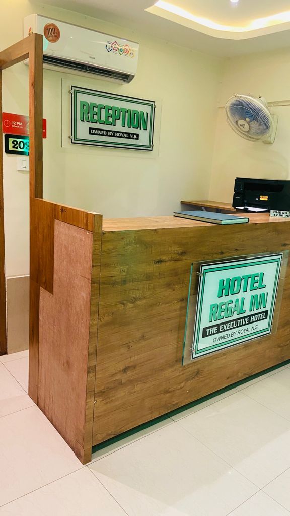 A reception desk with a sign indicating it is the reception area of Hotel Regal Inn, owned by Royal N.S.
