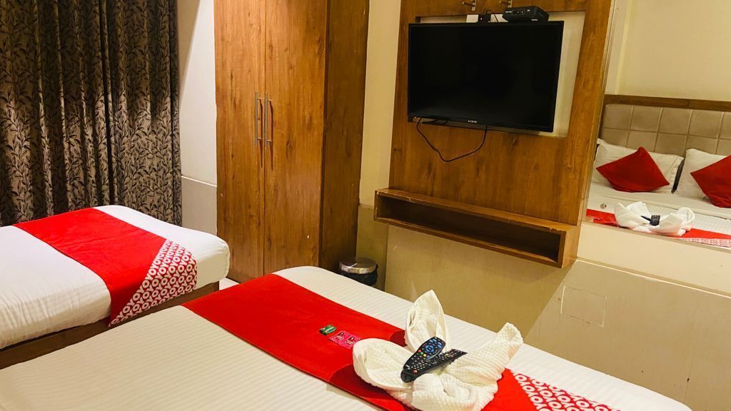 A hotel room with two beds, a TV, and a wooden wardrobe.