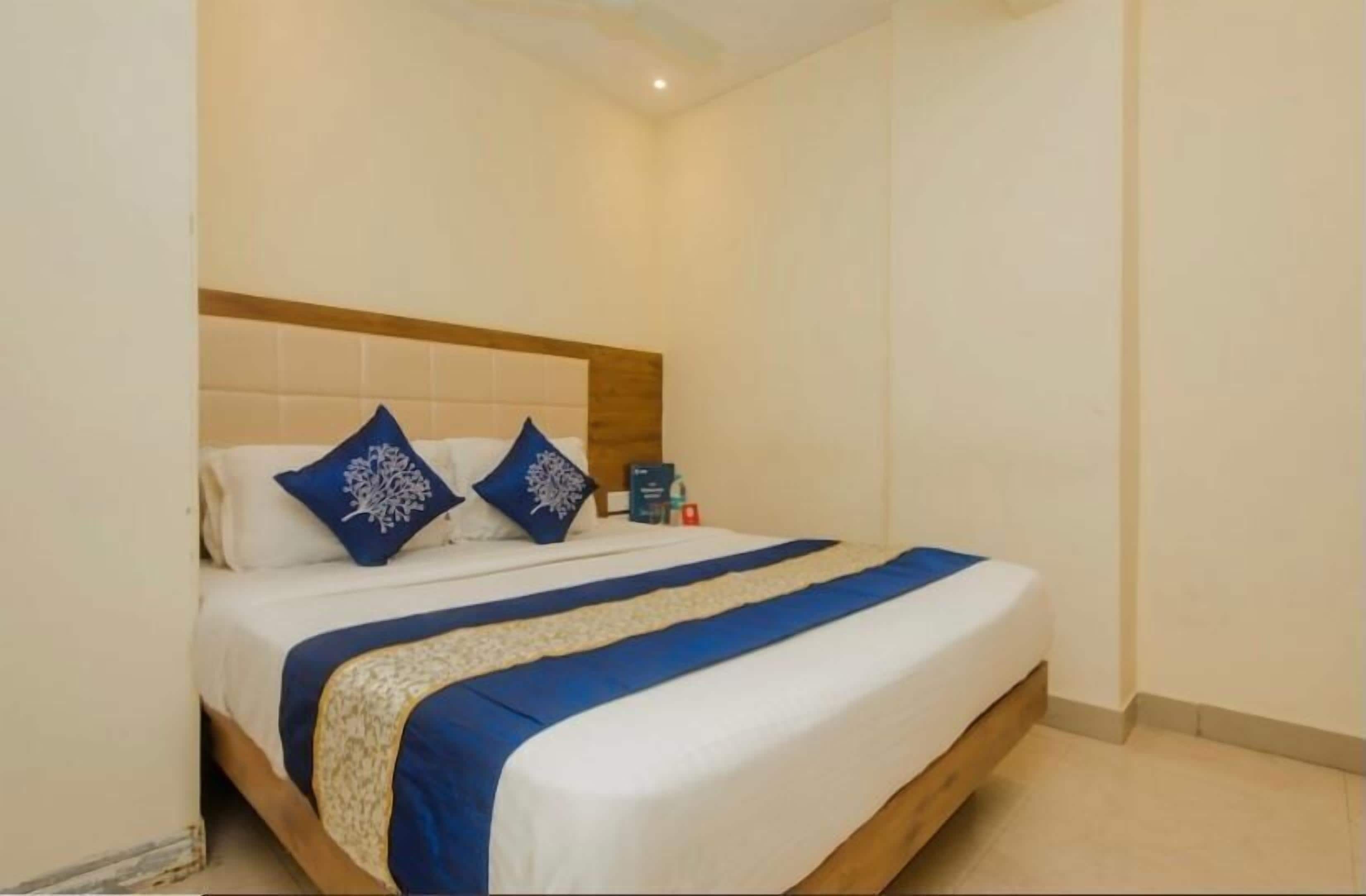 A neatly made bed with a wooden headboard, white and blue bedding, and a blue accent strip.
