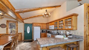 Una cocina rústica con armarios de madera, encimera de granito y un comedor con mesa y sillas de madera.