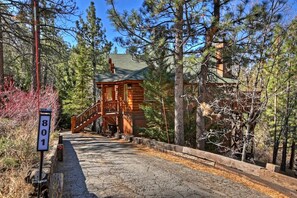 A cabin with a wooden exterior, a porch, and a staircase leading to a deck.
