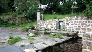 Ein Steingebäude mit einem kleinen Wasserkanal und Stufen, die zu einem Tor führen.