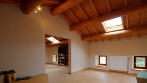 Ein geräumiges Loft mit hohen Decken, Holzbalken, einem Oberlicht und einer eingebauten Bücherreolen.