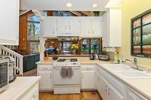 A kitchen with white cabinets, a stove, and a sink.