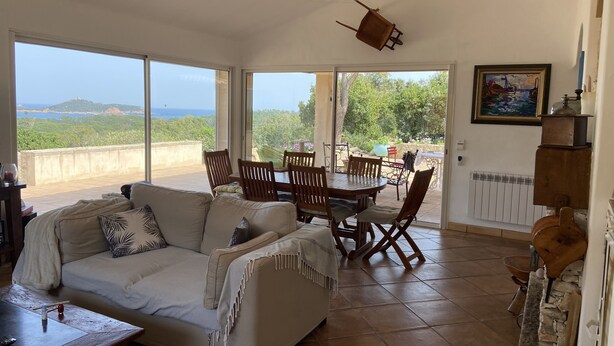 A spacious living area with a sofa, dining table, and chairs, large windows offering a view of the sea and greenery. - Villa between sea and mountains 15 minutes from the beach (zonza)