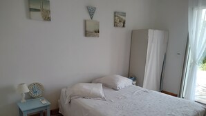 A bedroom with a bed, a bedside table with a lamp, a mirror, and artwork on the wall. - Villa between sea and mountains 15 minutes from the beach (zonza)