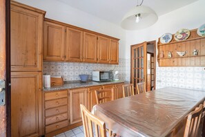 A kitchen with wooden cabinets, a microwave, and a dining table.
