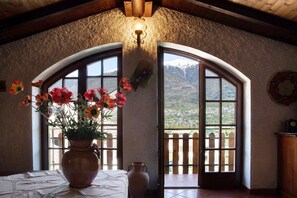 A room with a large vase of flowers, a bed, and a view of mountains through arched windows. - Holiday Home 'In Valtellina Da Valter E Lella' with Mountain View, Wi-Fi & Air Conditioning (Colorina)