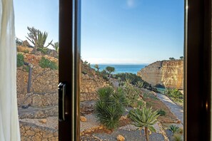 Paisaje costero con terreno rocoso, cactus y una vista despejada del mar.