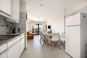 Una cocina moderna con comedor, armarios blancos y un refrigerador.