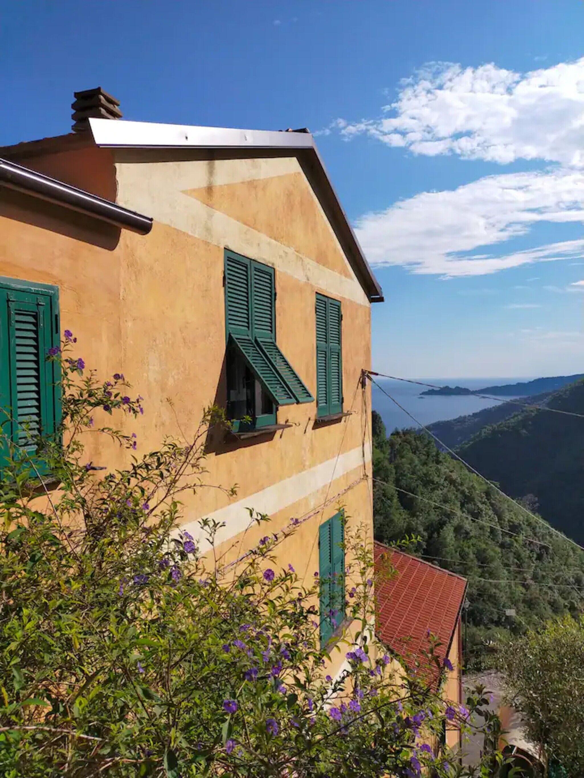 Ein Gebäude mit grünen Fensterläden, einem geneigten Dach und Blick auf ein Tal.