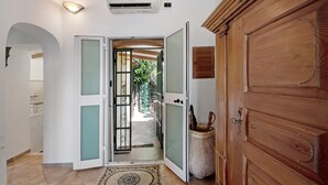 A hallway with a wooden door, a glass door leading outside, and a tiled floor.