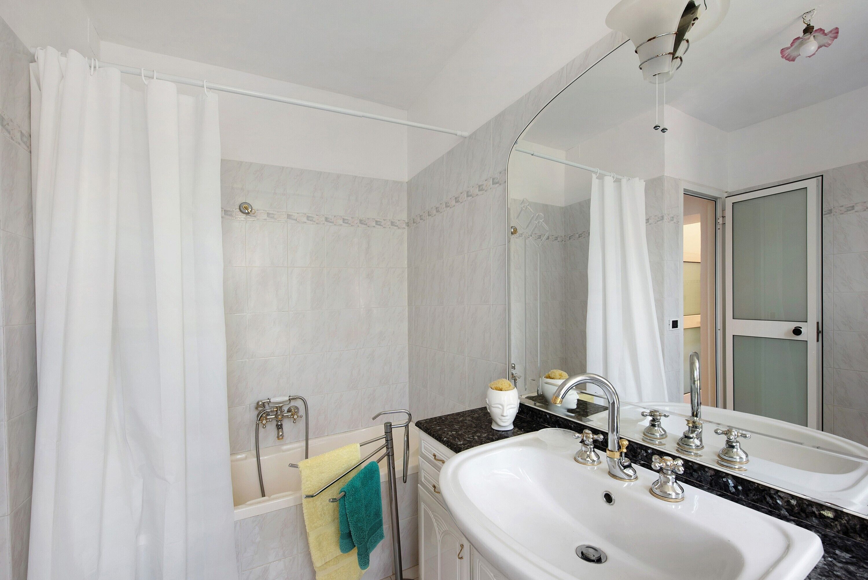 Ein Badezimmer mit einer Badewanne, einem Waschbecken mit Spiegel und einer Duschvorhang.
