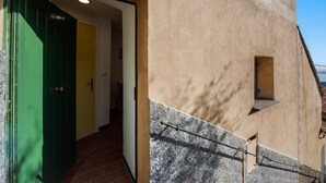 Entrada de um edifício com uma porta verde, uma pequena janela e uma escadaria.