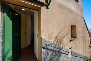 A building entrance with a green door, a small window, and a staircase leading up.