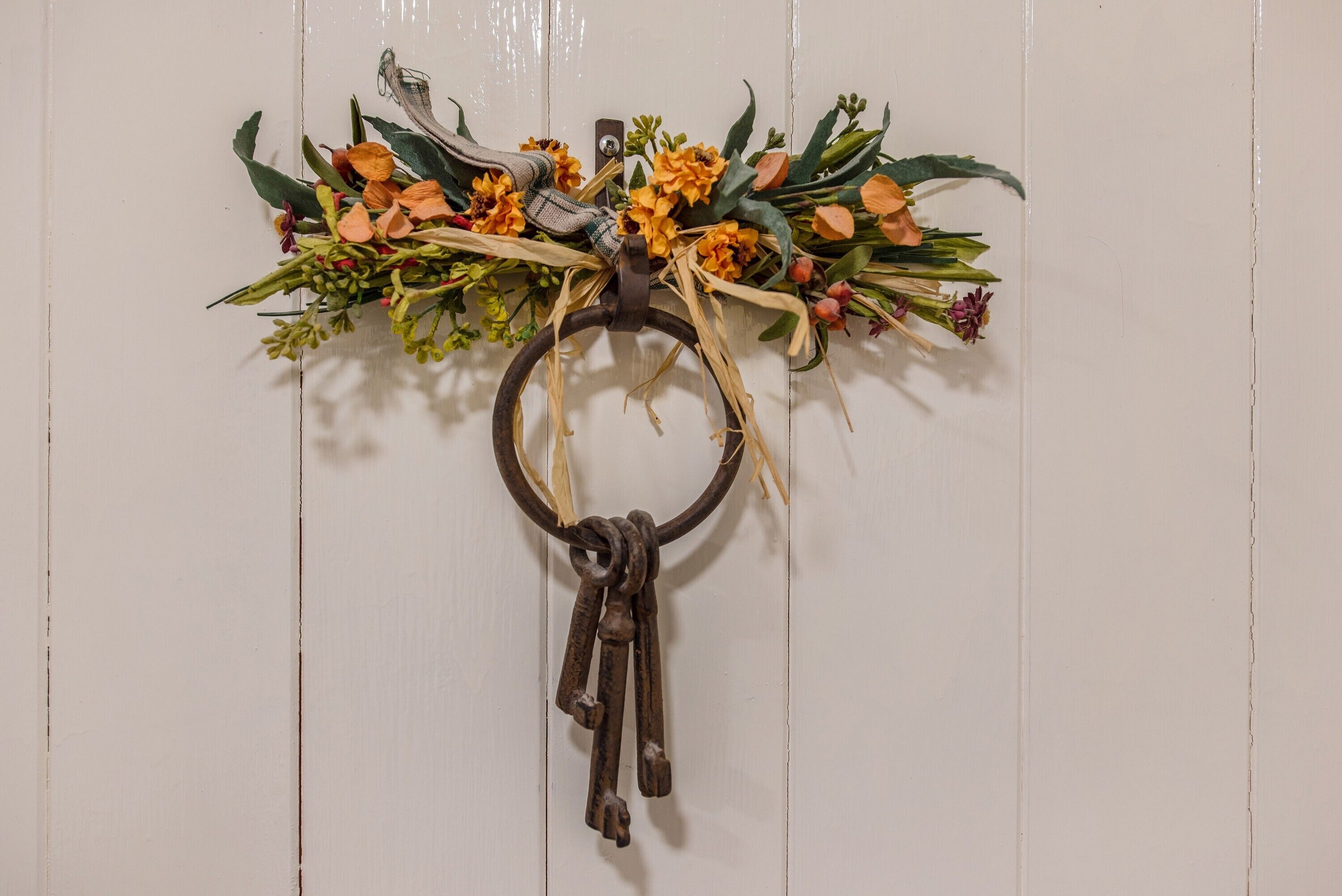 Ein an der Wand befestigter Schlüsselring mit Blumenarrangement und rustikalem Anhänger.