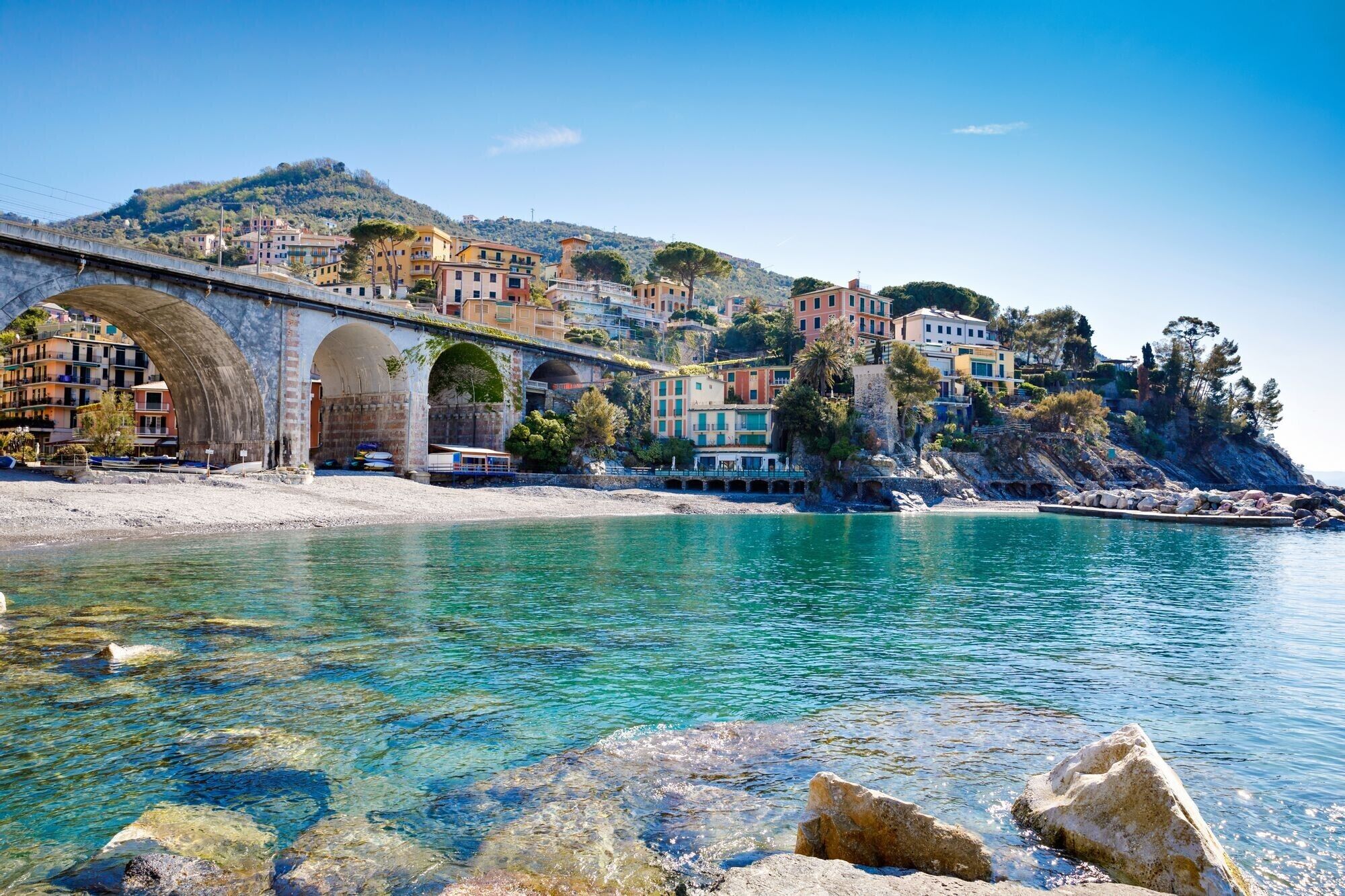 Une ville côtière qui se distingue par son imposant pont de pierre, ses eaux turquoise et limpides, et ses bâtiments aux couleurs vives.