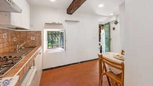 Cozinha com fogão, pia e janela. Há uma área de jantar com mesa e cadeiras.