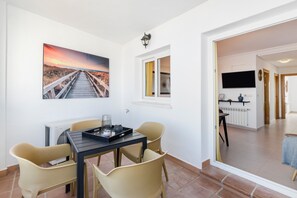 A dining area with a table, chairs, a tray, and a painting of a sunset over a bridge.