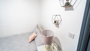 A bedroom with a bed, a bedside table with a lamp, and two wall-mounted shelves. - Spacious Studio Near City Centre! (Birmingham)