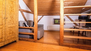 Un dormitorio tipo loft con vigas de madera a la vista, un sofá, un armario y un radiador.