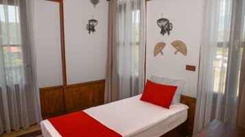A bedroom with a bed, wooden paneling, two wall-mounted lamps, and sheer curtains.