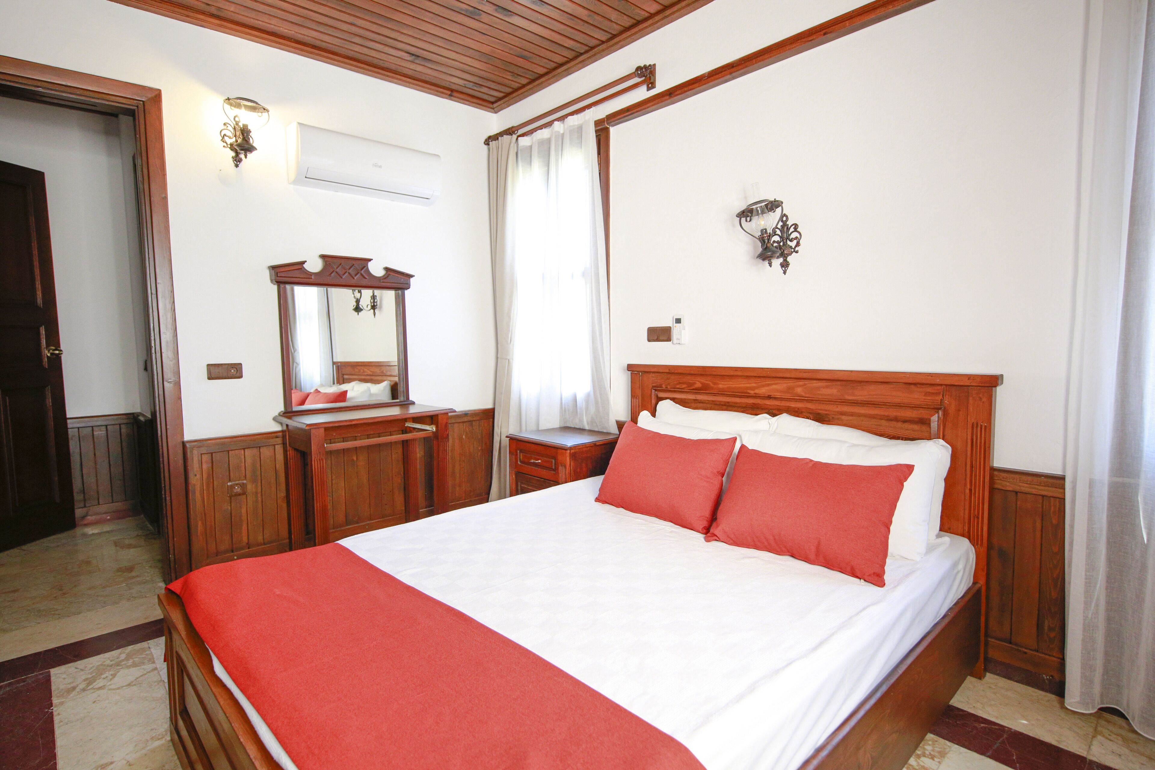 Een hotelkamer met een houten bed, een houten dressoir, een spiegel en een nachtkastje.