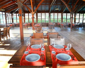 Enjoy meals in this dining area with high ceilings and large windows offering views of the surrounding greenery.