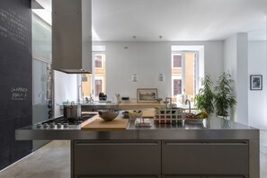 Una cocina moderna con una isla central, electrodomésticos de acero inoxidable y una pizarra con escritura.