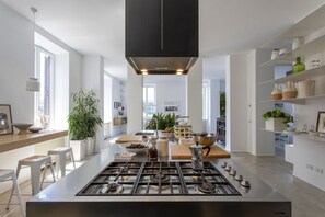 A modern kitchen with a central island, stainless steel appliances, and white cabinetry. - GuestHost - Large and bright 200sqm apartment, able to accommodate up to 7 people, located on the 3rd floor with elevator (not suitable for disabled people) of a building dating back to the 19th century. The property overlooks Piazza Fanti's garden and i (Roma)