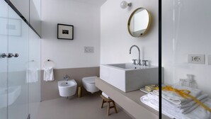 A modern bathroom with a large sink, a mirror, a bidet, and a glass shower enclosure.