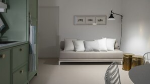 A minimalist room with a sofa, a desk, a lamp, and framed artwork on the wall.
