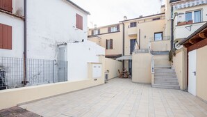 Une cour avec un sol carrelé, une clôture en métal et un escalier menant à un niveau supérieur.