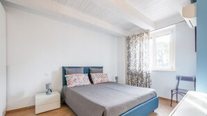 Une chambre à coucher comprenant un lit, une table de chevet, une chaise, une fenêtre avec des rideaux et un bureau.