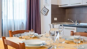 Une table à manger dressée avec des assiettes, des verres et un pichet, avec une cuisine en arrière-plan.