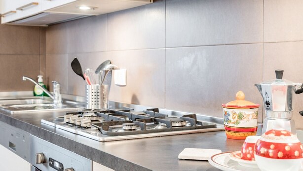 Une cuisine moderne équipée d’une cuisinière à gaz, d’appareils électroménagers en acier inoxydable et d’un dosseret carrelé.