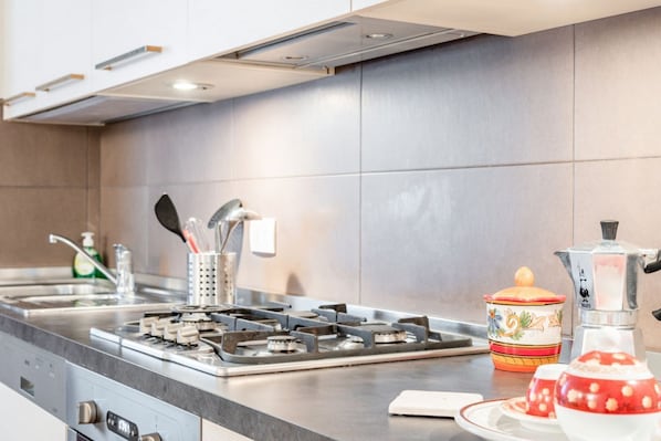 A modern kitchen with a gas stove, stainless steel appliances, and a tiled backsplash.