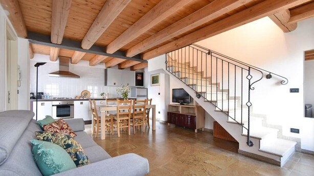 Ein modernes Interieur mit Holzboden, einer Treppe, einem Essbereich und einem Wohnzimmer mit Sofa.
