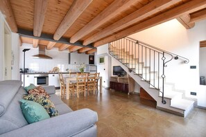 Un interior moderno con techo de madera, una escalera, una zona de comedor y un salón con sofá.