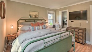 Ein Schlafzimmer mit Bett, Nachttisch, Lampe, Kommode und einem Fernseher.