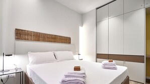 A modern hotel room with a large bed, a bedside table with a lamp, and a wardrobe. - Yellow Donatello Charming suite by Hospity (Milano)