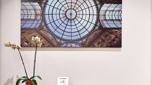 Un interior moderno con una consola de madera, una orquídea en maceta y una obra enmarcada en la pared.