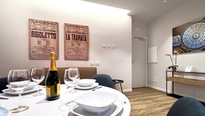 Un comedor con una mesa redonda dispuesta para cuatro personas, una botella de champán y dos carteles en la pared.