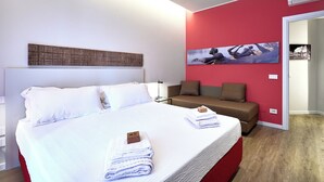 Una habitación de hotel moderna con una cama grande, un sofá y una pared de acento roja.