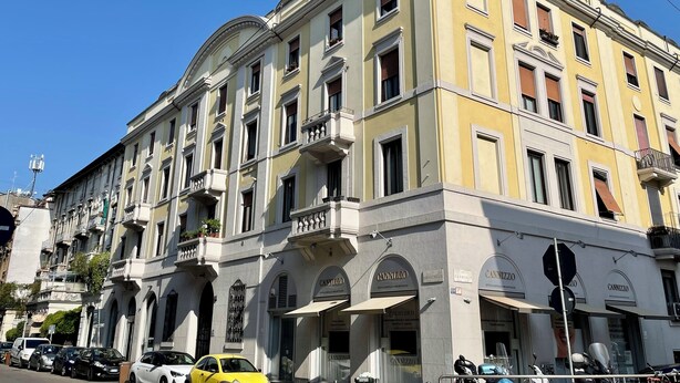 Un edificio de varios pisos con estilo arquitectónico clásico, que presenta ventanas y balcones de arco.