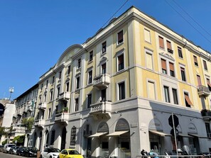 Ein mehrstöckiges Gebäude mit Geschäften im Erdgeschoss, erkennbar an den betrieblichen Schildern.