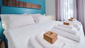 A neatly made bed with white linens and a cork block with a logo on it.