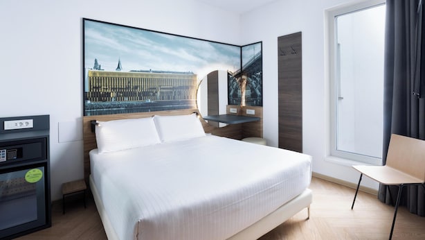 A modern hotel room with a large bed, a desk with a computer, a chair, and a large window. - B&B Hotel Maribor (Maribor)