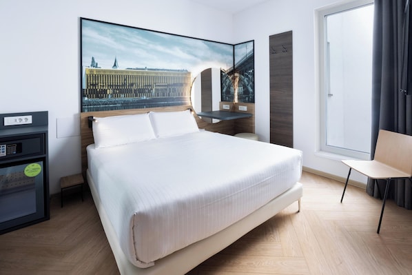 A modern hotel room with a large bed, a desk with a computer, a chair, and a large window. - B&B Hotel Maribor (Maribor)